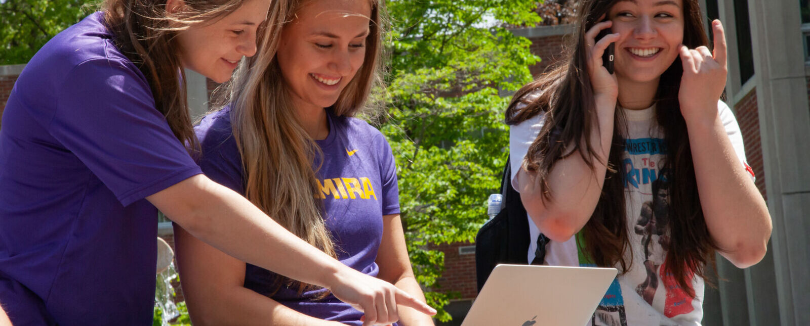Students looking at a laptop. 